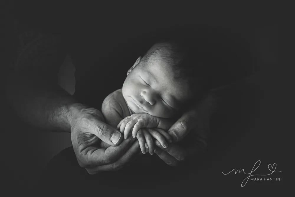 Foto neonato bianco e nero mani genitori - studio Roma | Mara Fantini Neonato addormentato cullato tra le mani dei genitori, foto in bianco e nero in studio a Roma