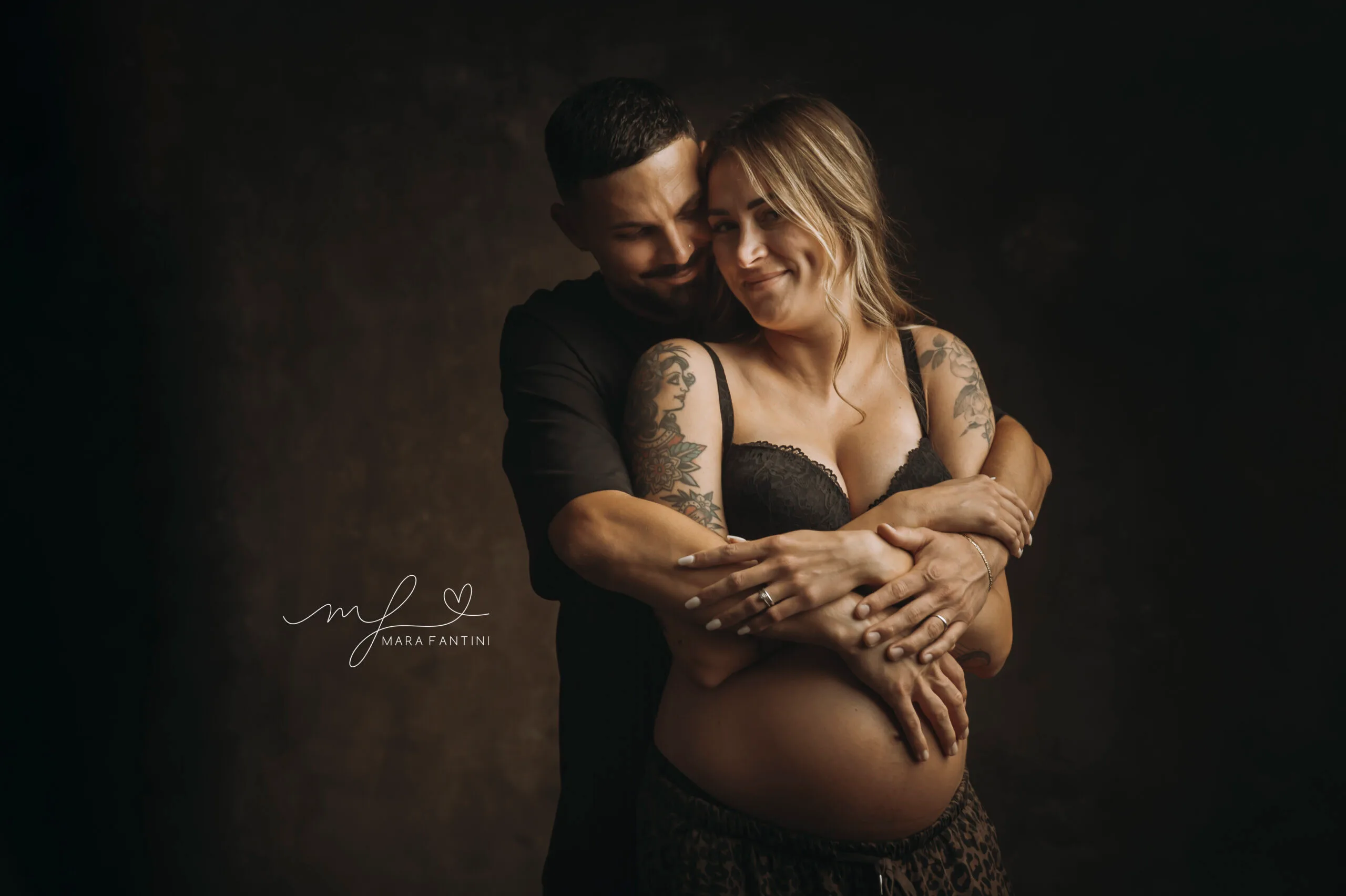 Coppia in attesa abbracciata durante un servizio fotografico di gravidanza Coppia in attesa che si abbraccia con tenerezza durante un servizio fotografico di gravidanza a Roma